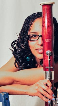 Side view of a Black woman in glasses holding a bassoon.