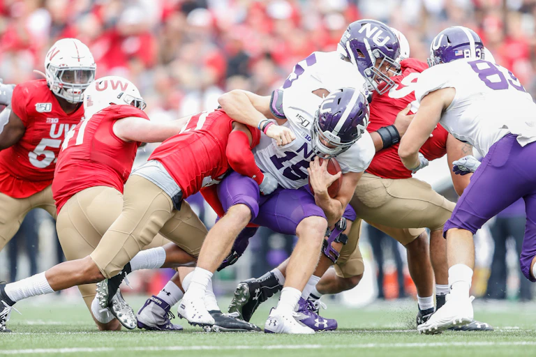 A football player is being tackled by an opposing team.