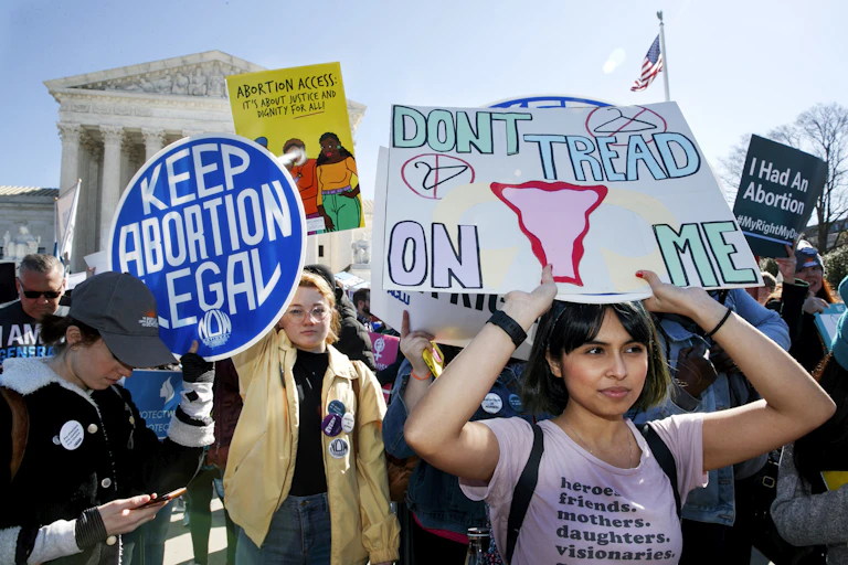 Protesters outside the Supreme court carrying signs that say Keep abortion legal, Don't tread on me and Abortion access