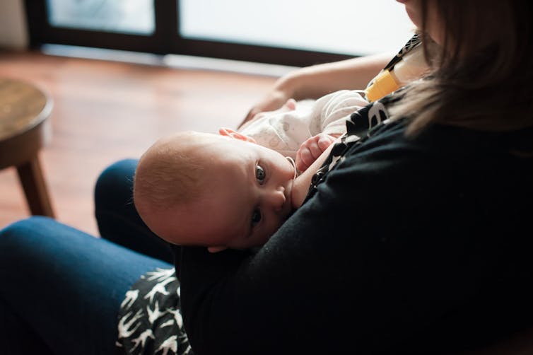 Woman breasfeeding baby using a breastfeeding supplementer