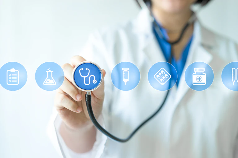 Una médica con fonendoscopio ante iconos de probeta, jeringuilla, bléster de pastllas, bote de medicinas, termómetro.