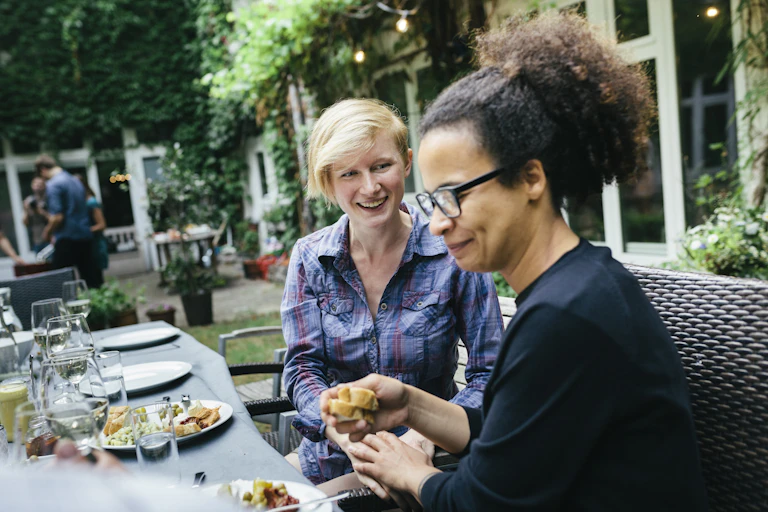smiling white woman seated with a Black woman who's turning her head away