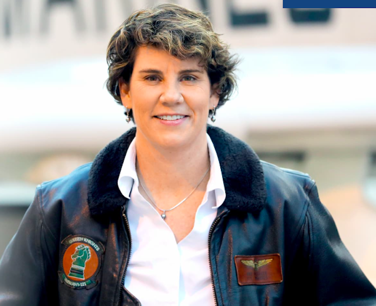 Amy McGrath in a flight jacket and open-collar shirt.
