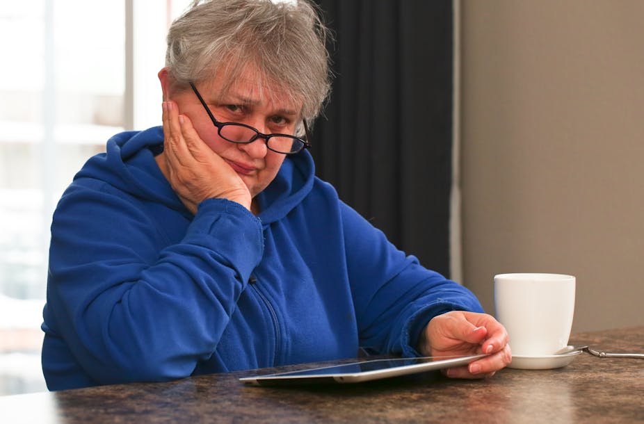 Woman in glasses sitting with tablet and cup of tea.