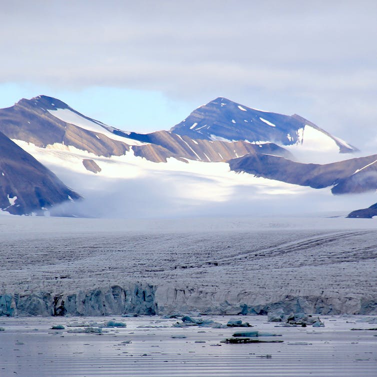 Large glacier flows into the sea. White in background and grey in the foreground.
