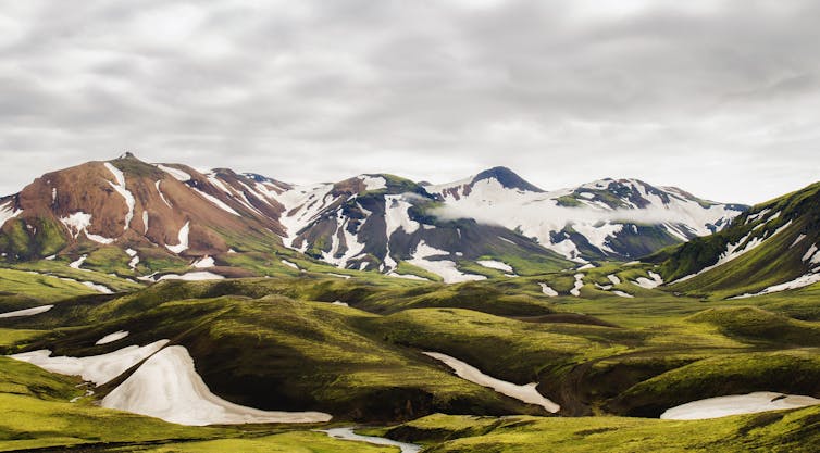 Large mountains with glaciers, grassy hills in foreground.