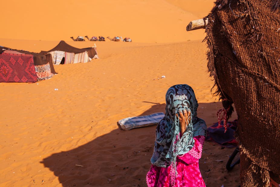A girl child covering her face with her hand.