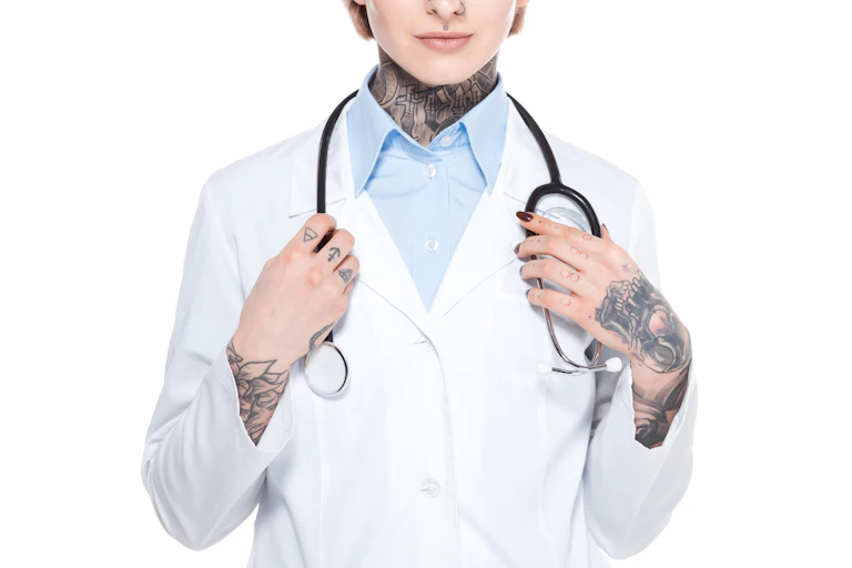 in a white medical jacket with tattoos on her neck and hands and a stethoscope around her neck