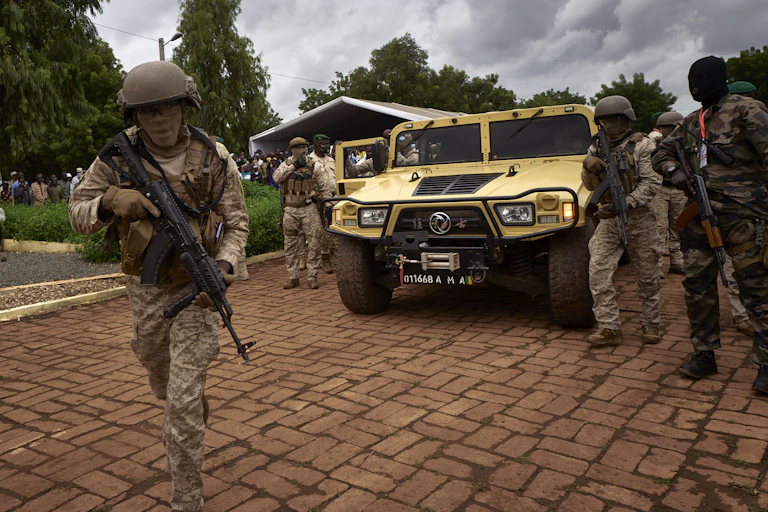 Armed and uniformed men with faces obscured by scarves surrounding a military vehicle