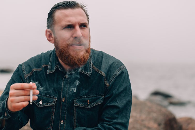 A man smokes a cigarette outdoors.