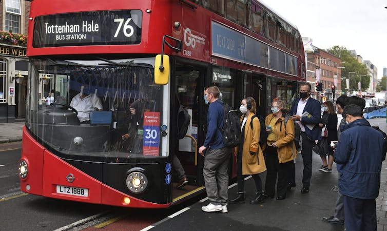 Londoners in mask line up for a bus
