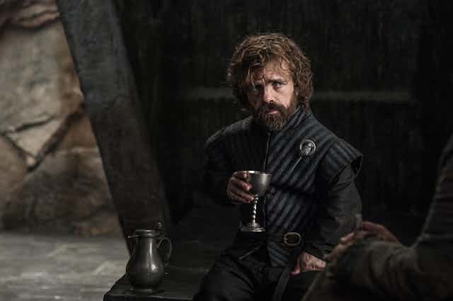 Tyrion Lannister de la série Game of Thrones, un verre à la main.