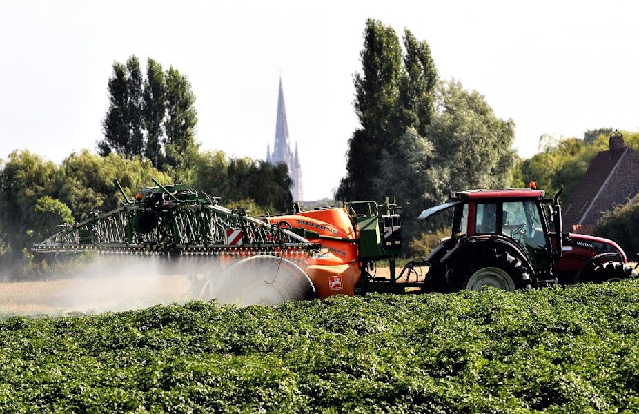 Un tracteur pulvérisant des pesticides sur des cultures.