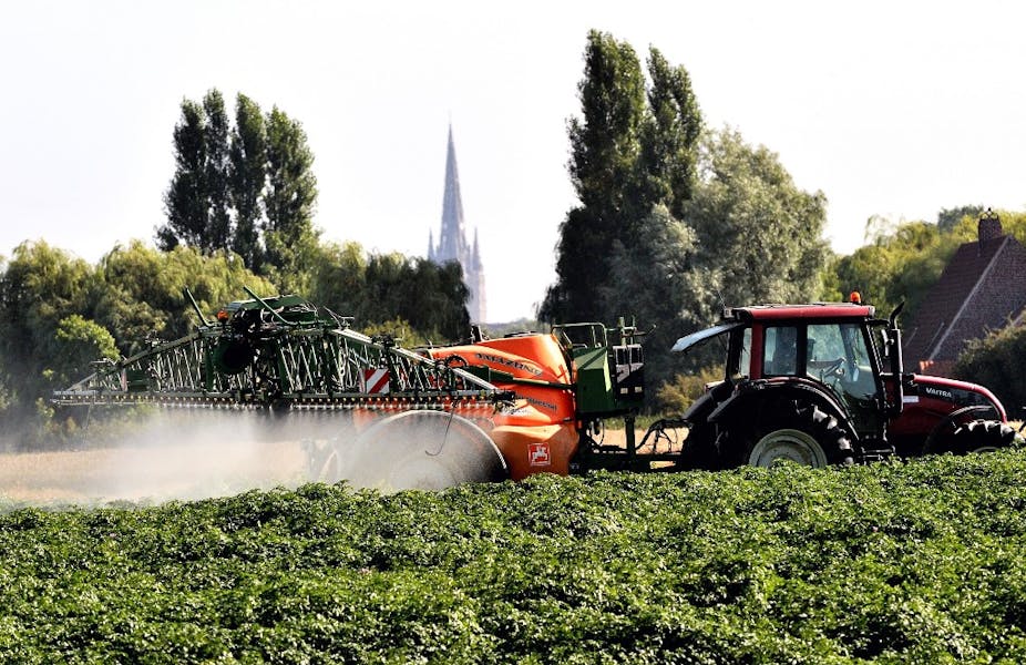 Un tracteur pulvérisant des pesticides sur des cultures. 