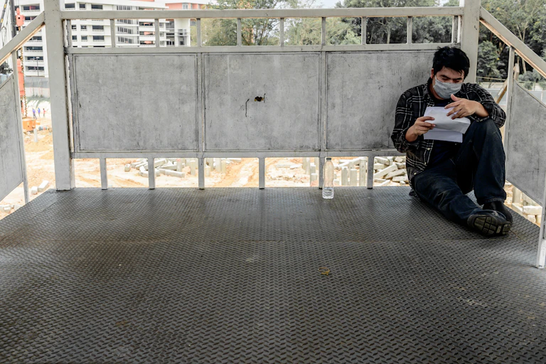 Un hombre con mascarilla en un bacón leyendo una carta de despido.