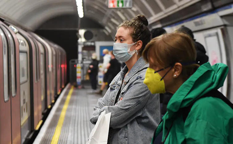 Commuters wearing face masks on a London Underground station platform.