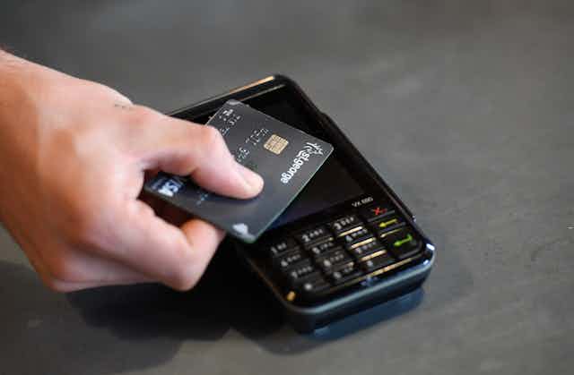 A credit card being tapped against an EFTPOS machine