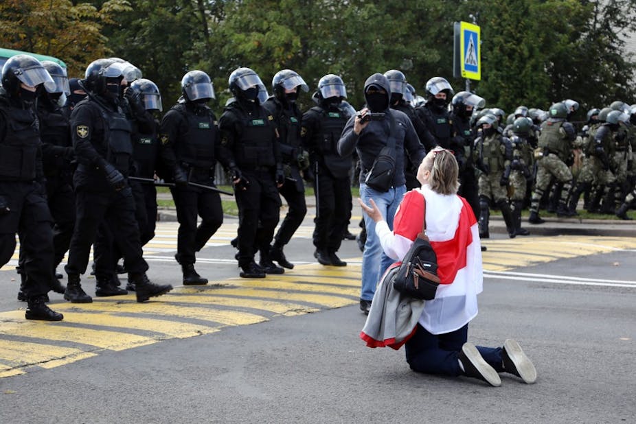 Une femme à genoux devant la police anti-émeutes