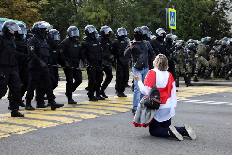 Une femme à genoux devant la police anti-émeutes