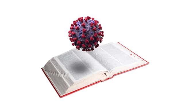 A 3D model of the coronavirus hovers over an open dictionary.