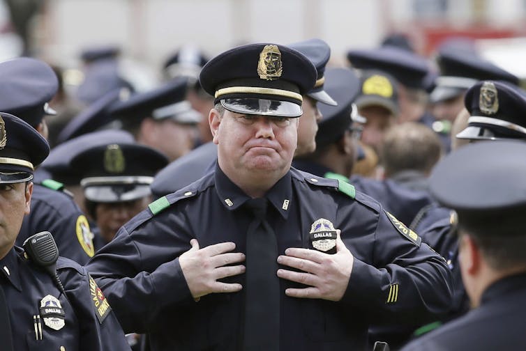 A police officer fights back tears at a memorial service.