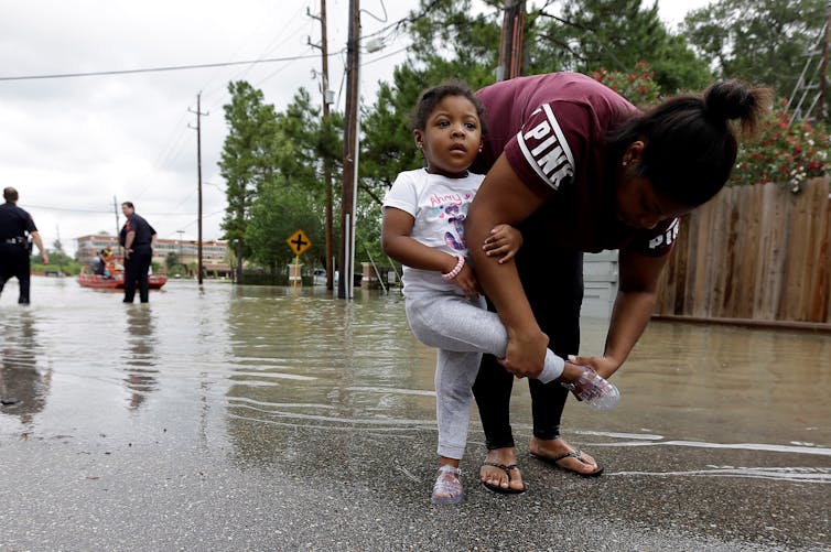 A woman puts her daughter's shoe on after they were rescued from a flooded apartment complex.