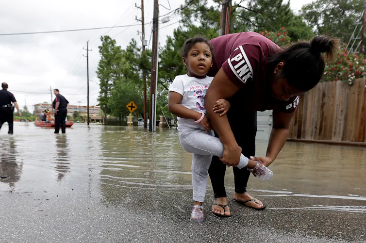 A woman puts her daughter's shoe on after they were rescued from a flooded apartment complex.