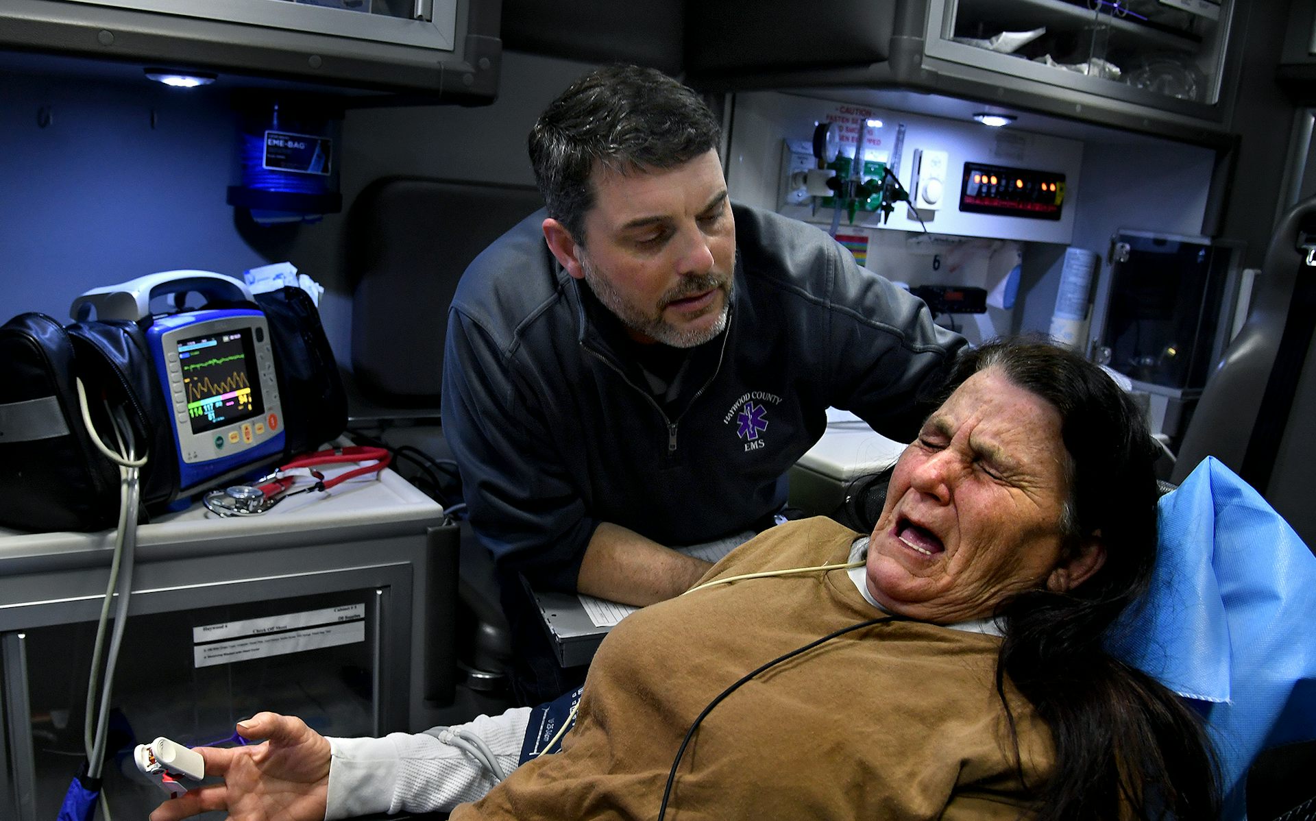 An EMT comforts and helps a woman injured in a car crash.