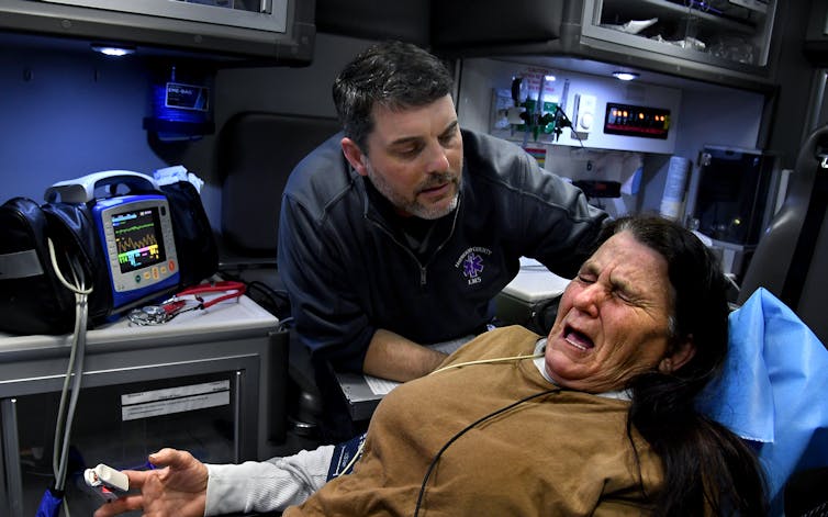 An EMT comforts and helps a woman injured in a car crash.