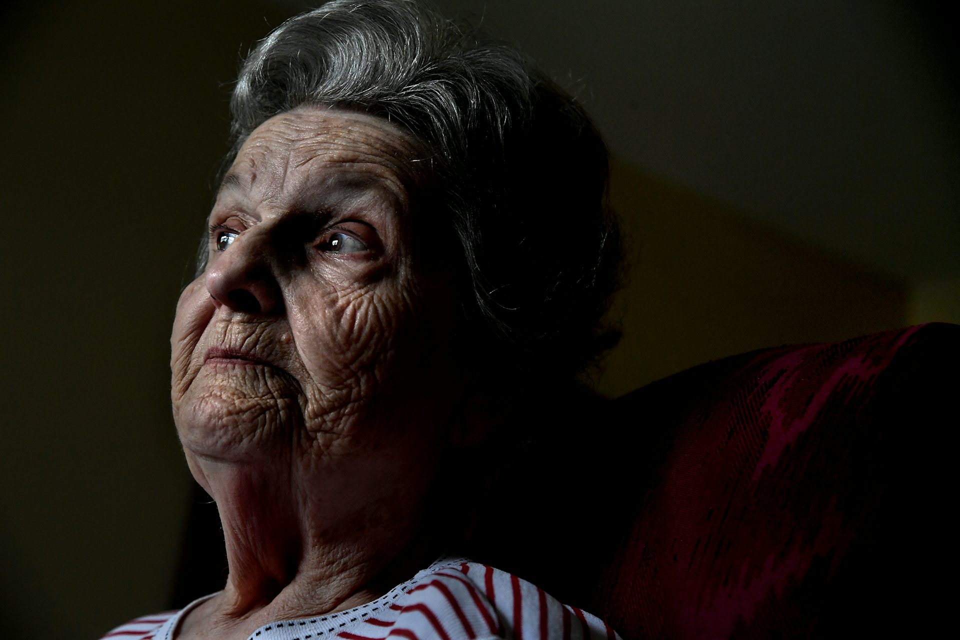 An older woman looks into the distance.