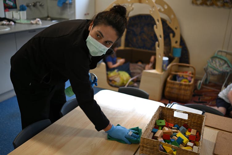 A childcare worker wipes down a table.