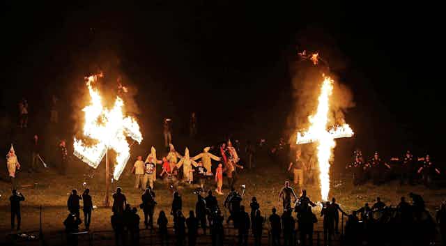 A burning swastika and cross at a Ku Klux Klan rally.