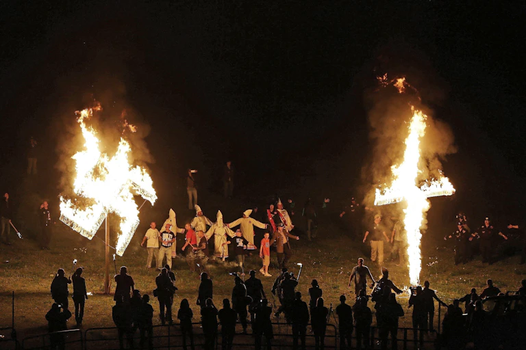 A burning swastika and cross at a Ku Klux Klan rally.