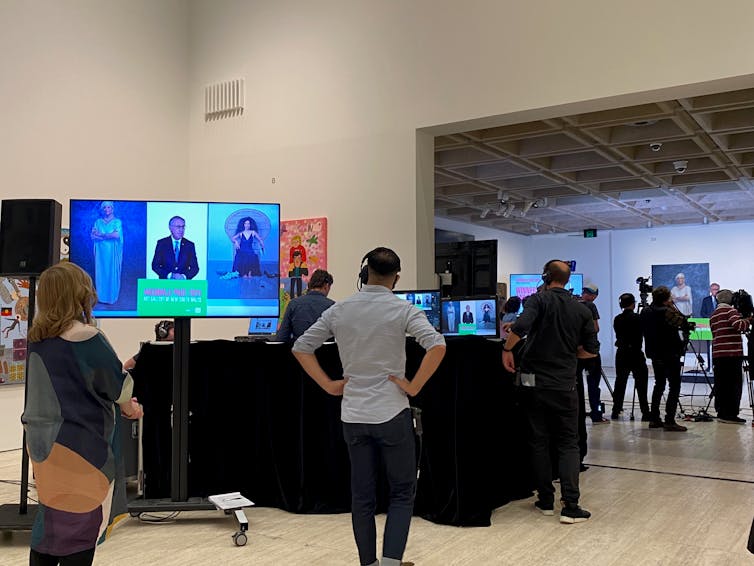 People standing around computers in art gallery.