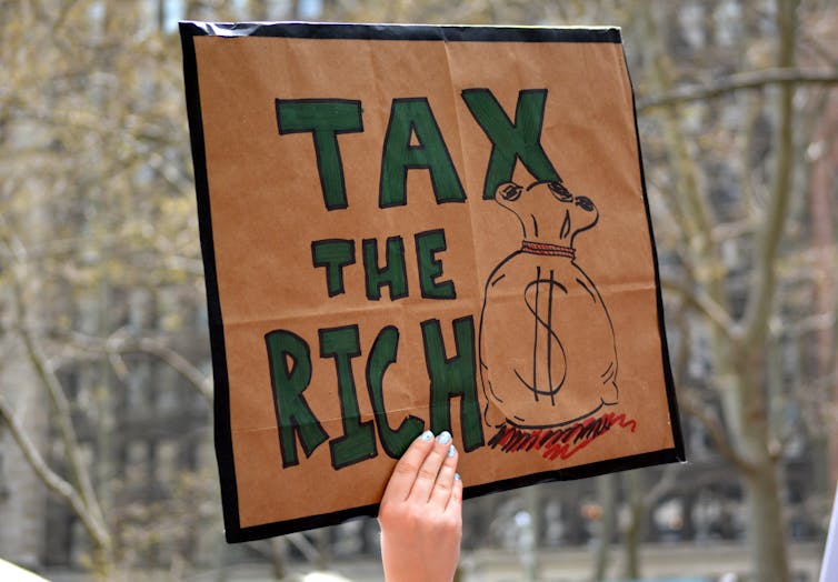 Protester holding up sign that says 'tax the rich'