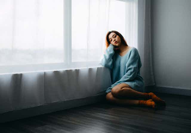 A woman sits by a window