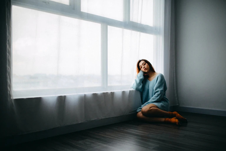 A woman sits by a window