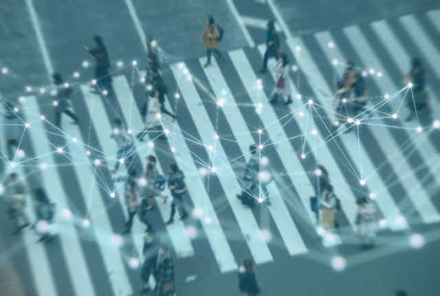 A network appears over a blurred birds-eye photograph of people on a crosswalk