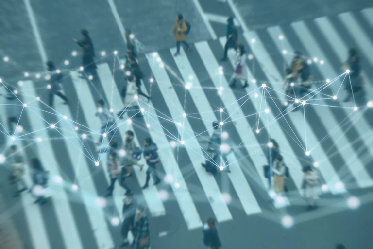 A network appears over a blurred birds-eye photograph of people on a crosswalk