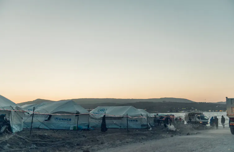 Tents are seen at dawn behind a fence.