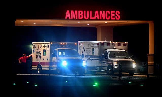 Two ambulances with lights on at nighttime. 
