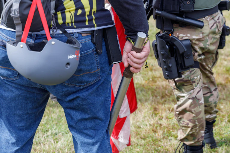 A man holding a club next to an armed man.