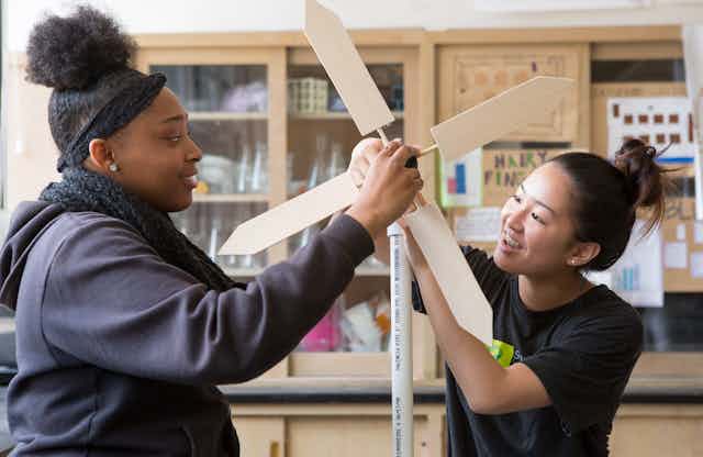 Two students handle a hand-made wind turbine.