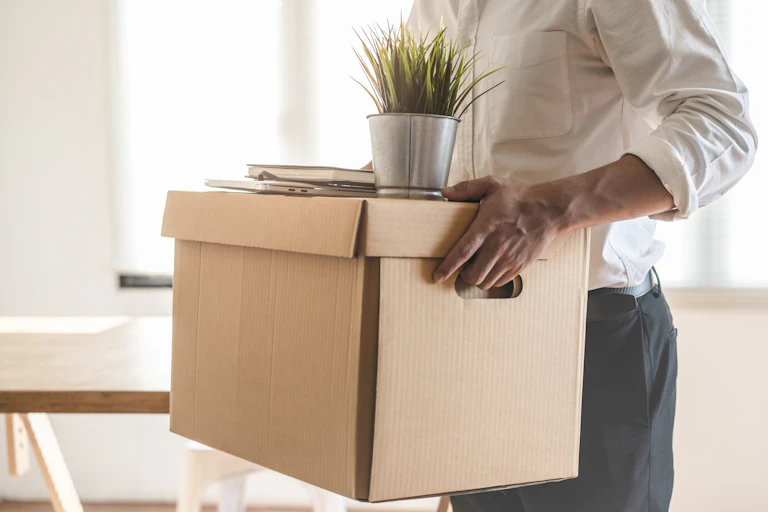 Man carrying packed up belongings after being sacked