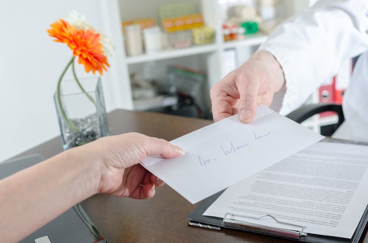 A doctor handing a patient a referral letter