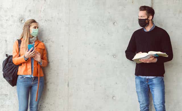 Male and female students wearing masks standing a distance from eachother. 