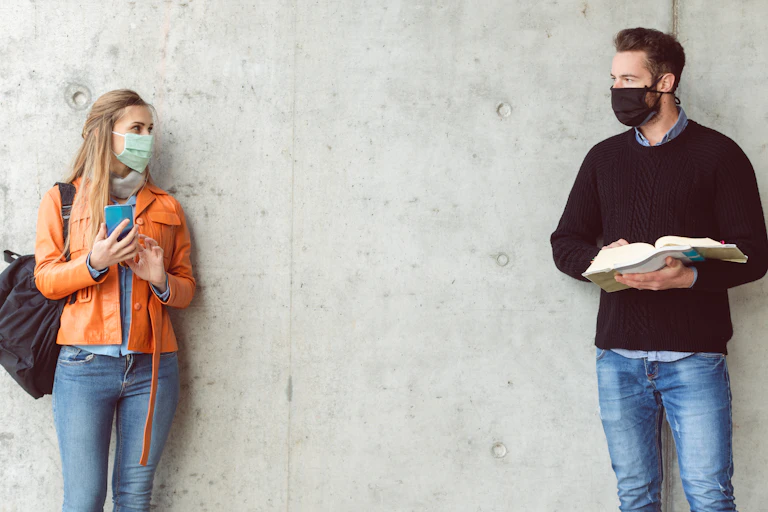 Male and female students wearing masks standing a distance from eachother.