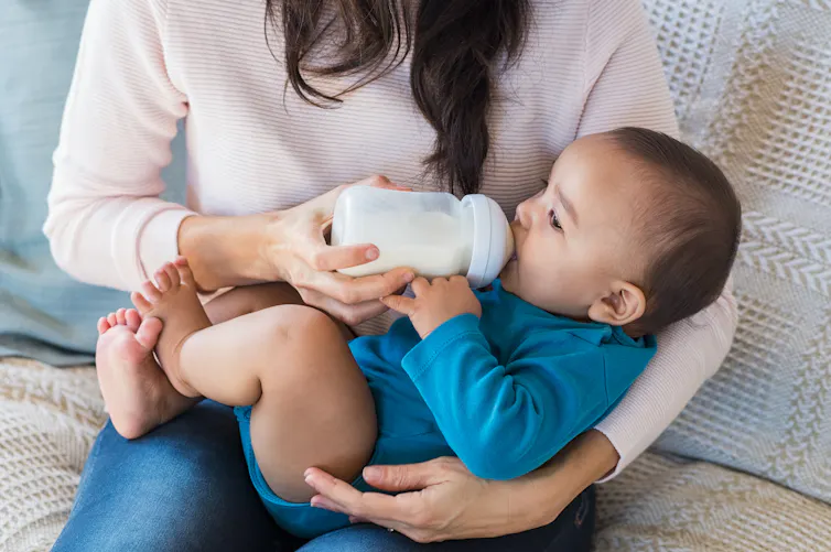 Mother bottle feeds her infant.