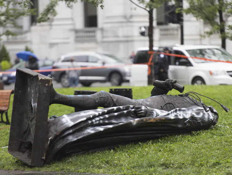 A statue of Sir John A. MacDonald lies on the ground.