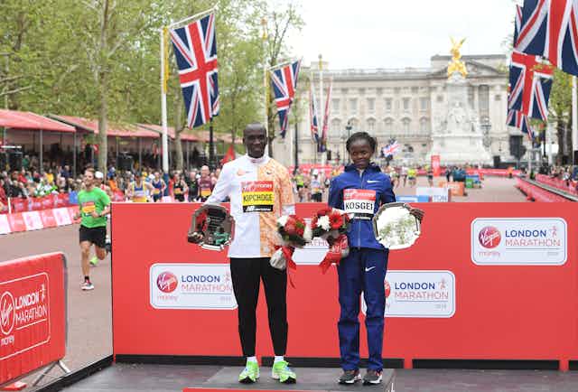 London Marathon men's race winner, Eliud Kipchoge, and women's race winner, Brigid Kosgei pose at the medal ceremony during the 2019 London Marathon.